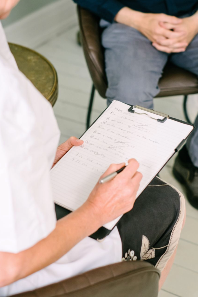 view over the shoulder of a student writing on paper taking notes in a consultation