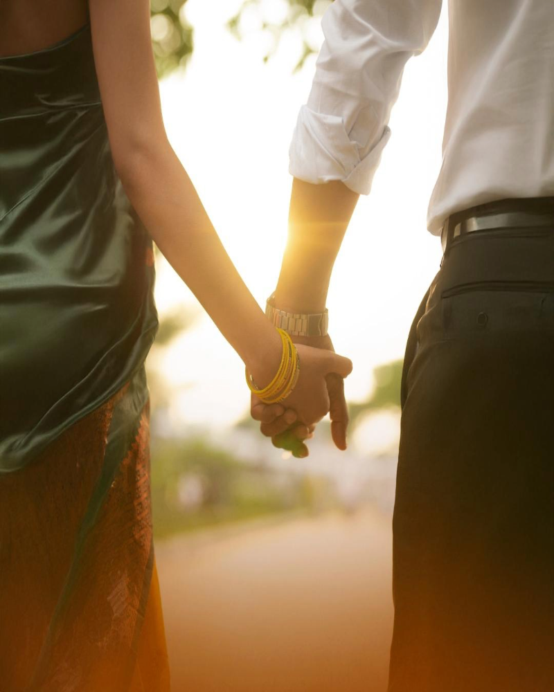 Couple male and female holding hands, silhouette in the sunset