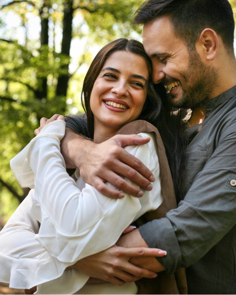 couple in an embrace in the forest, both smiling