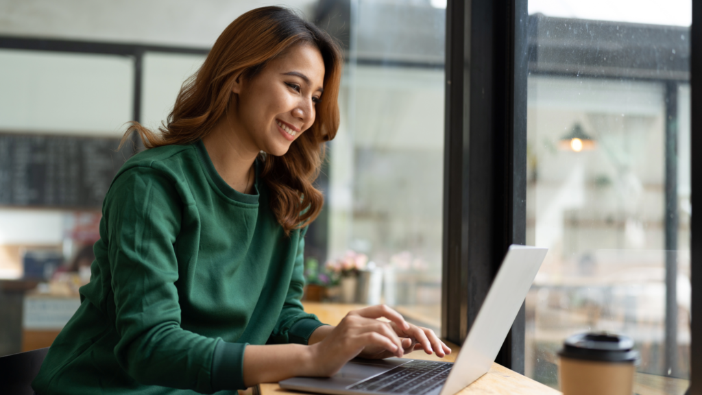 Woman booking an acupuncture appointment on laptop in coffee shop