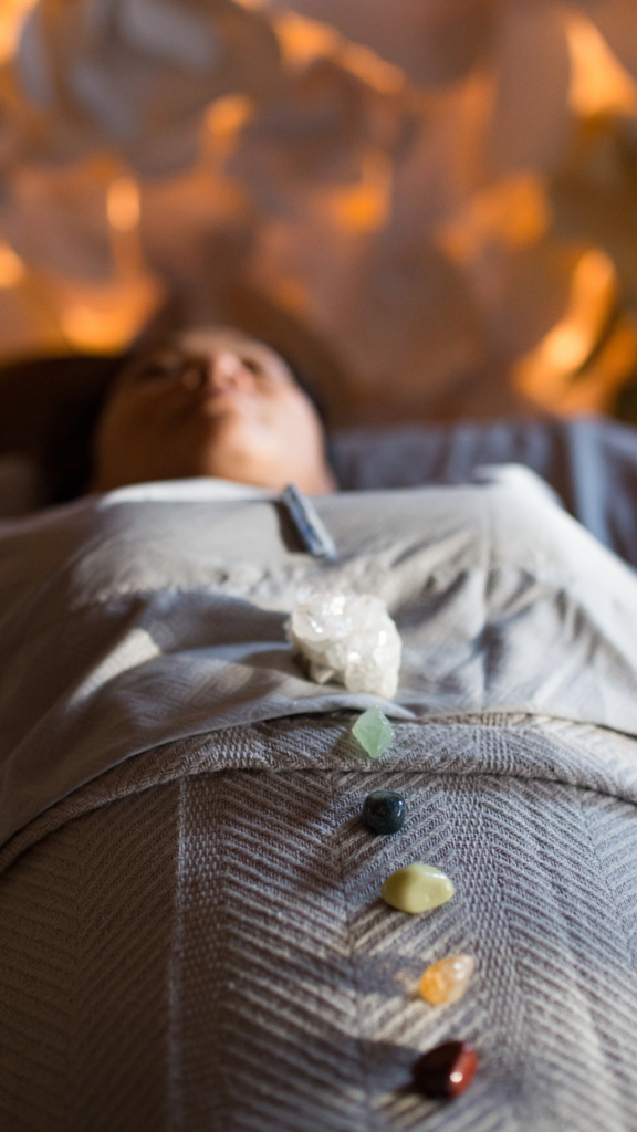 Person lying on their back with healing crystals on their chakras for balance